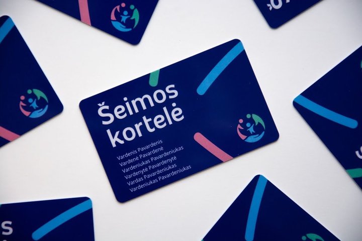 Tamsiai mėlyna Šeimos kortelė padėta ant plokščio paviršaus, aplink ją ratu atsitiktine tvarka išdėstytos kitos kortelės.