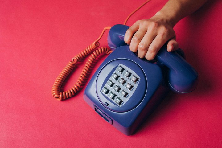 Telefonas, už kurio ragelio griebiasi ranka.