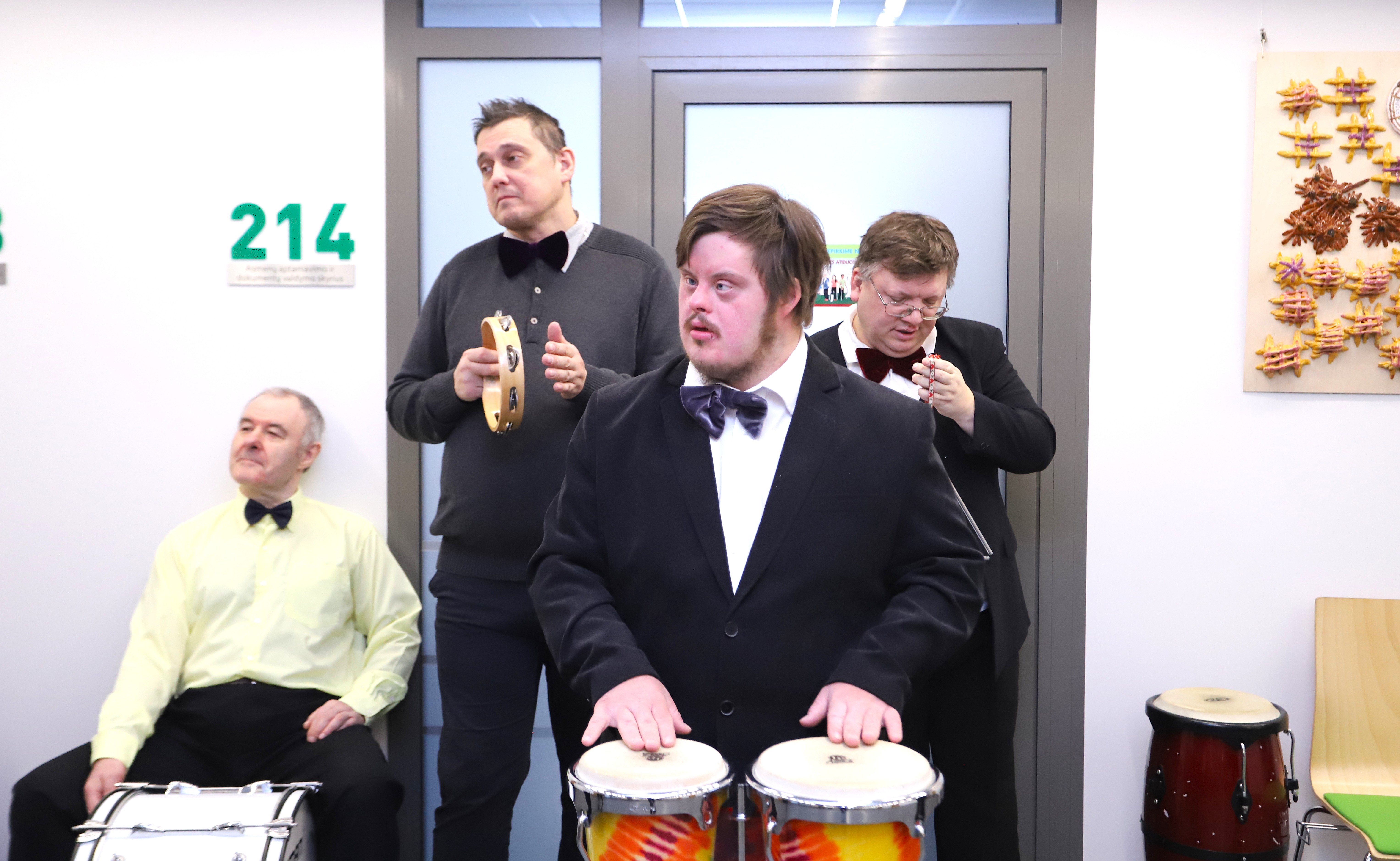 Dienos centras "Šviesa" muzikos grupė, gyvai atlieka dainą Agentūroje. Keturi vyrai turi po instrumentą, vienas - didelį būgną, kitas barškutį, trečias muša būgnelius, o ketvirtas - trikampį.